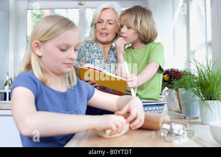Grand-mère et petits enfants (8-9) dans la cuisine Banque D'Images