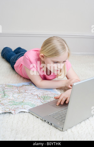 Girl (8-9 lying on floor using laptop, portrait Banque D'Images