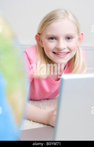 Girl (8-9 lying on floor using laptop, portrait Banque D'Images