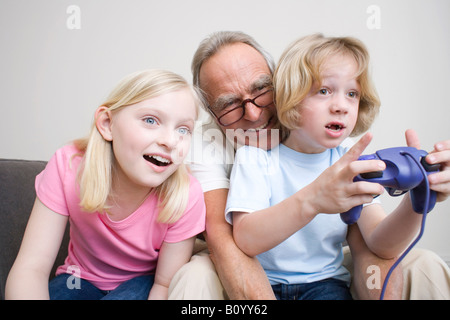 Grand-père et ses petits-enfants (8-9) playing video game, portrait