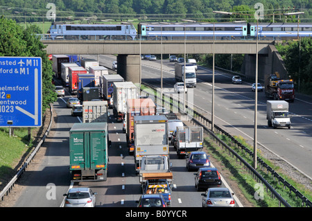 Transport Choice M25 autoroute nez à queue trafic lent regardant le train rapide de voyageurs sur le pont ferroviaire sortie 28 Brentwood Essex Angleterre Royaume-Uni Banque D'Images