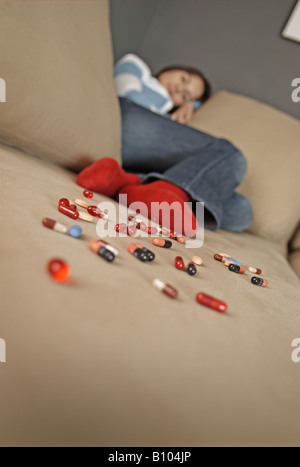 Femme assise sur le canapé, appuyée avec pills Banque D'Images