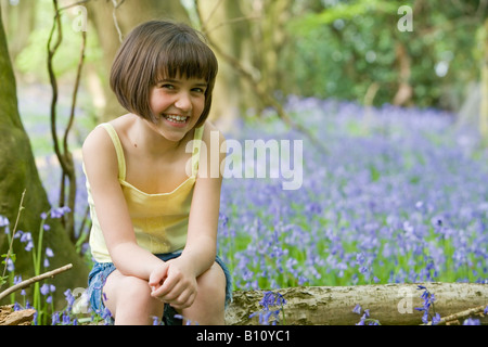 Jeune femme enfant assis dans un champ de bluebells avec espace pour copier Banque D'Images