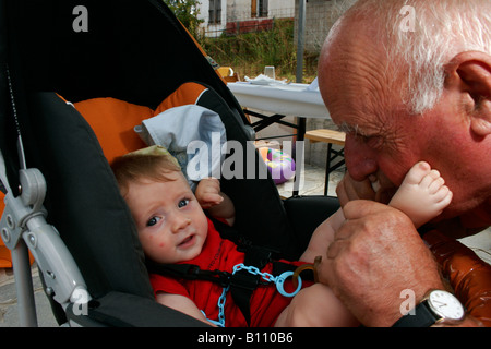 Un bébé et son grand-père jouant en été Banque D'Images