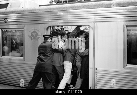 Les banlieusards d'être poussé dans un train roulant de Yokohama à Tokyo à l'heure de pointe du matin. Banque D'Images