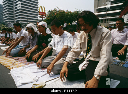 Les musulmans de faire une prière de l'après-midi à côté d'un Mc Donalds en sortie de la ville de Jakarta en Indonésie Banque D'Images