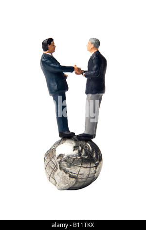 Deux figurines se serrer la main en se tenant debout sur un globe de la terre Banque D'Images