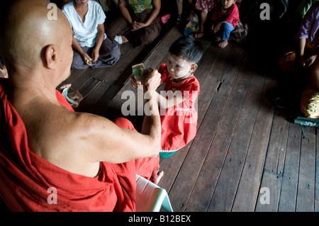 Un moine bouddhiste donne un don à une jeune fille atteinte du cyclone dans un monastère de la commune de Kyauktan à Yangon Myanmar, en Birmanie Banque D'Images