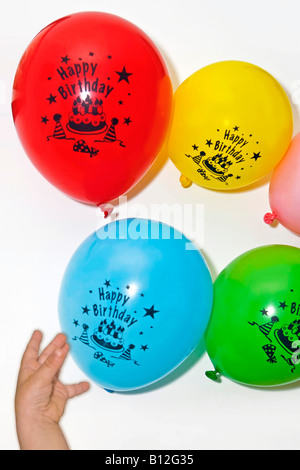 Petit garçon essayant d'atteindre des ballons d'anniversaire Banque D'Images