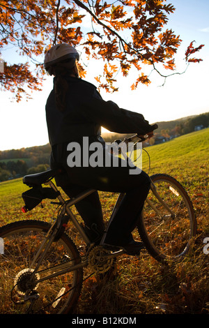 D'ÂGE MOYEN EN BONNE SANTÉ PLUS MATURE WOMAN RIDING BIKE SEUL À L'EXTÉRIEUR SUR LOCATION Banque D'Images