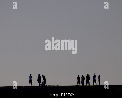 Silhouette d'un groupe d'adolescents sur le sommet d'une colline au crépuscule. Banque D'Images