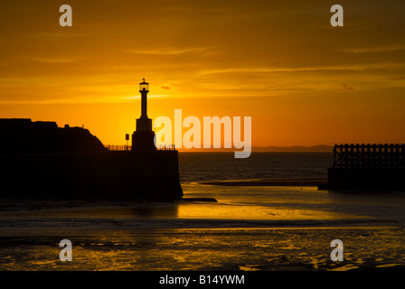 Coucher de soleil derrière le phare et mur du port de Bristol, Cumbria, Angleterre, Royaume-Uni Banque D'Images