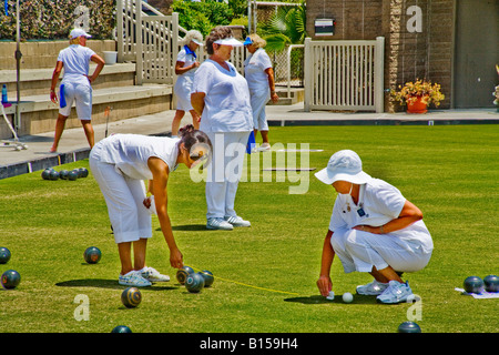 Règlement portant les uniformes blancs deux joueurs femme mesurer la distance entre deux boules de bowling sur gazon à la concurrence Banque D'Images