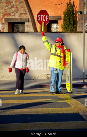 Brigadier scolaire hispanique rue des contrôles de trafic que les élèves de l'école élémentaire de la Californie du Sud et les parents arrivent en AM Banque D'Images