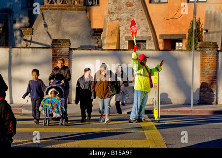 Brigadier scolaire hispanique rue des contrôles de trafic que les élèves de l'école élémentaire de la Californie du Sud et les parents arrivent en AM Banque D'Images