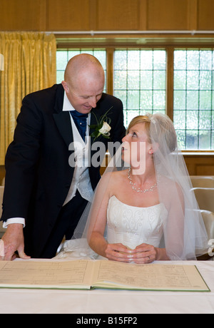 Un couple nouvellement marié viennent de signer leur certificat de mariage dans la sacristie de l'église. Banque D'Images