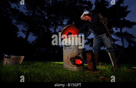 Céramiste Raku Dave Harrison en utilisant son four poubelle dans les bois près de son studio de Sussex. Photo par Jim Holden. Banque D'Images