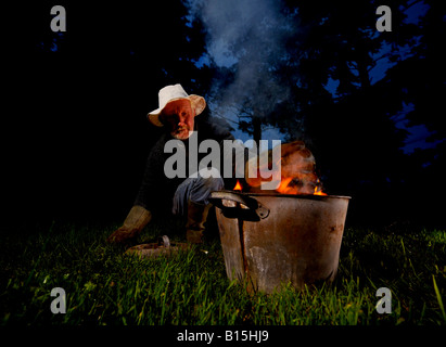 Céramiste Raku Dave Harrison en utilisant son four poubelle dans les bois près de son studio de Sussex. Photo par Jim Holden. Banque D'Images