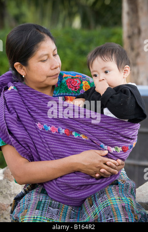 Maya une femme portant des vêtements traditionnels tissés à la main par elle-même ou sa famille et porter un bébé dans une écharpe Banque D'Images