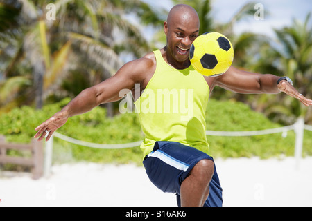 African American man bouncing soccer ball on knee Banque D'Images