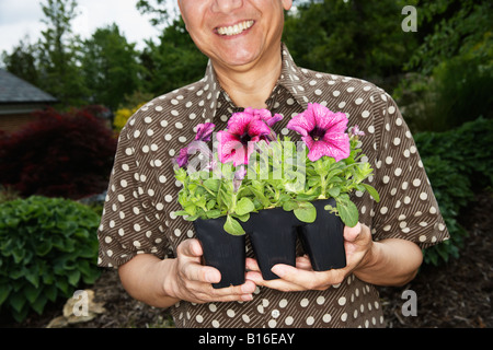 Senior Asian man holding potted plants Banque D'Images