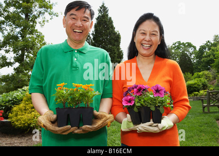 Senior Asian couple holding potted plants Banque D'Images