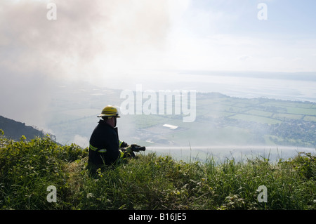 Fireman aborde l'ajonc d'incendie au Knockagh Monument, le comté d'Antrim Banque D'Images