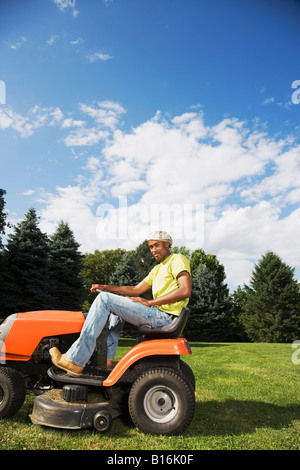 African American man mowing lawn Banque D'Images