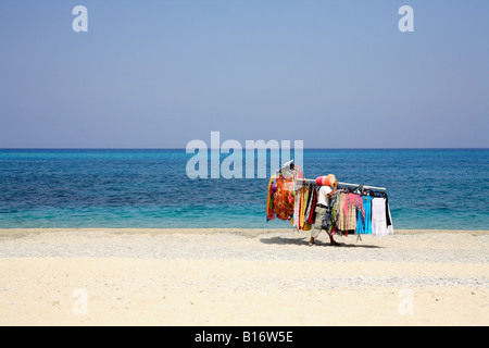 Un vendeur de plage sable promenades le long de la valeur comptable d'une grande charger des marchandises à vendre à torists et vacanciers. Banque D'Images