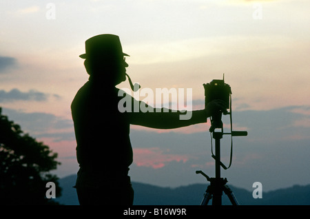Un photographe de fumer la pipe et avec une caméra 35mm sur un trépied photographie un Blue Ridge Mountain sunset Banque D'Images