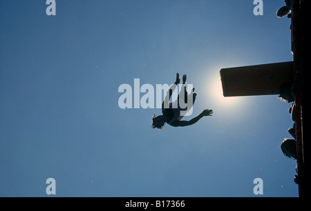 Un garçon dives off un plongeoir relié à un gros catamaran sur le lac Billy Chinook par une chaude journée de juillet Banque D'Images