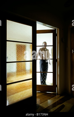 L'homme par double vitrage portes d'intérieur dans une salle sombre Banque D'Images