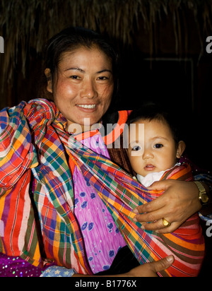 Une jeune mère de la tribu Akha au Lisu lodge tenant son bébé en costume traditionnel dans le nord de la Thaïlande Banque D'Images