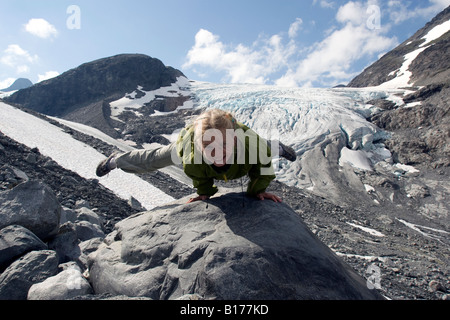 Huit ans fille blonde la gymnastique acrobatique de la scène en face de glacier à la Norvège à Jotunheimen Banque D'Images