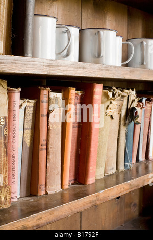 Livres et tasses sur une étagère dans le bâtiment de l'école dans le village abandonné de Tyneham, Dorset Banque D'Images