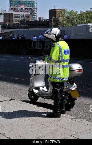 Agent de soutien communautaire de la Police métropolitaine debout à côté de son scooter Banque D'Images