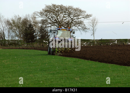 Un tracteur New Holland appartenant à un entrepreneur agricole laboure un champ Banque D'Images