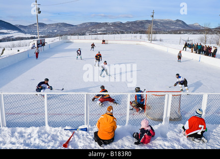 Match de hockey joué sur une patinoire extérieure sur un agréable samedi après-midi, Les Éboulements, Québec, Canada. Banque D'Images