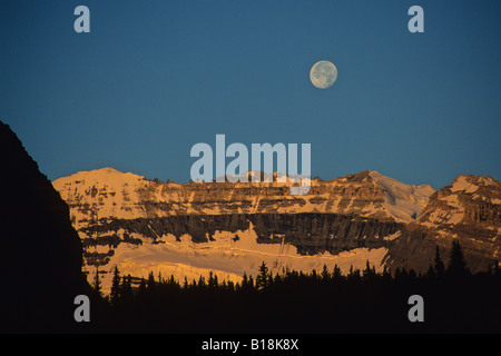 La lune au-dessus du Mont Victoria le matin alpenglow Lake Louise, Banff National Park, Alberta, Canada. Banque D'Images