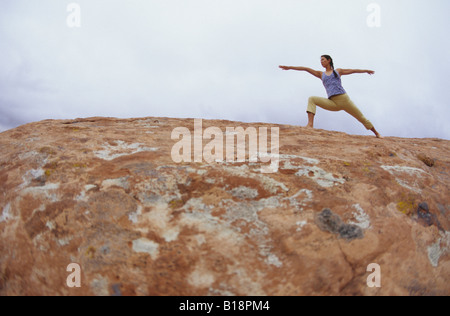 Une jeune fille faisant du yoga sur les roches rouges dans la région de Moab, Utah, United States Banque D'Images