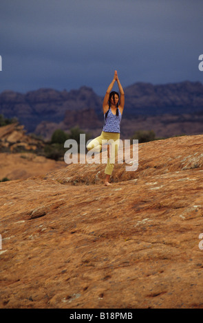 Une fille pratiquant le yoga sur une fonctionnalité de Red Rocks dans Moab, Utah, United States. Banque D'Images