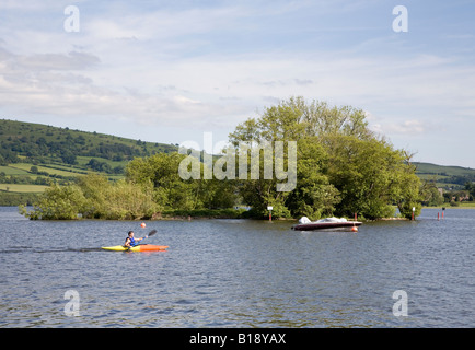 Kayak homme passé l'île par l'homme ou crannog dans Llangorse Lake Wales UK Banque D'Images