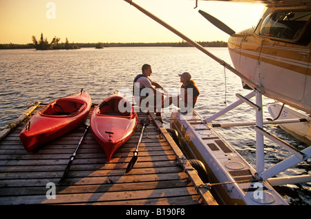 Couple avec kayaks sur dock, Otter Falls, parc provincial de Whiteshell, Manitoba, Canada. Banque D'Images