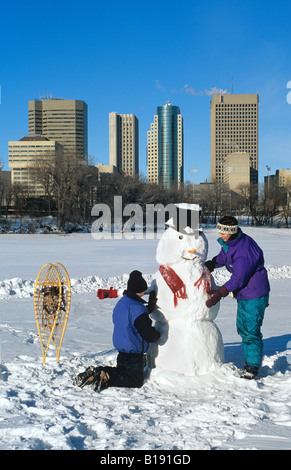 Faire un bonhomme de neige le long de la rivière Rouge avec en arrière-plan, Winnipeg, Manitoba, Canada Banque D'Images