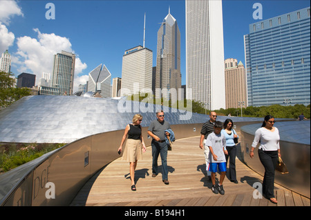 Parcs Chicago Illinois personnes marchant sur BP Bridge design Frank Gehry dans le Parc du millénaire les courbes en acier inoxydable skyline Banque D'Images