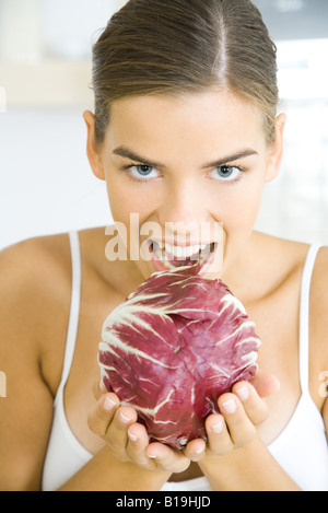 Woman holding up tête de laitue radicchio, prêt à prendre une bouchée de c Banque D'Images