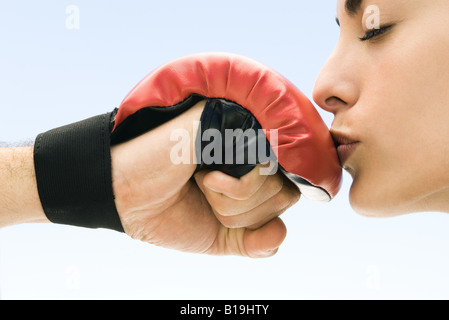 Woman kissing man's boxing glove, yeux clos, side view Banque D'Images