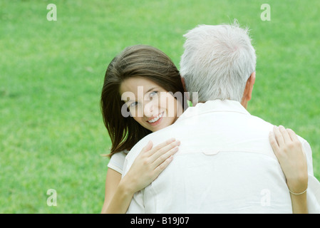 Teen girl embracing grand-père, smiling at camera Banque D'Images