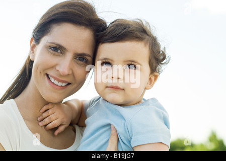 Mother holding baby, smiling at camera, portrait Banque D'Images