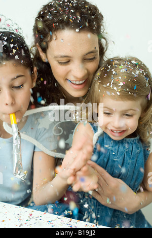 Jeune femme et deux petites filles jetant des confettis, tout sourire Banque D'Images